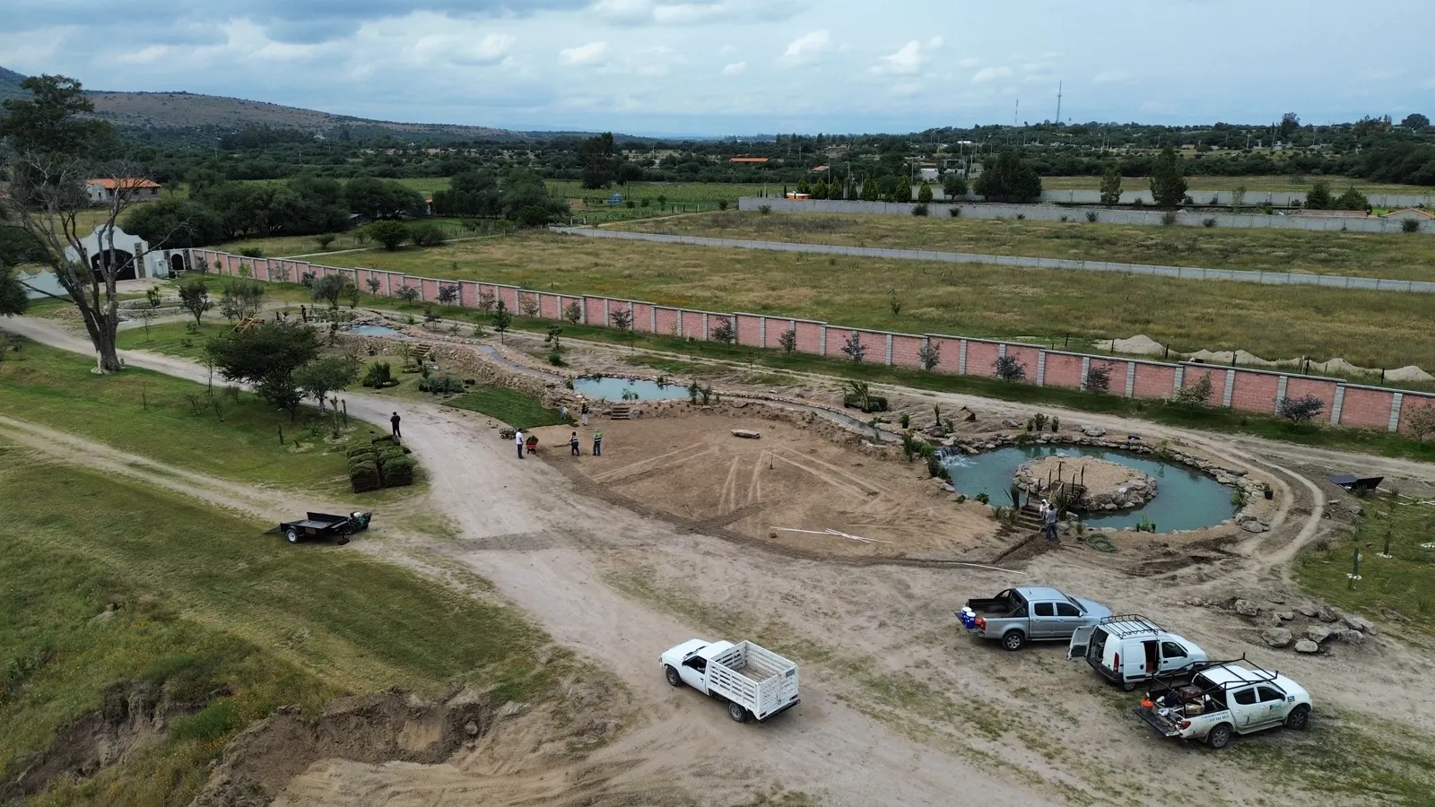 Vista aérea de un estanque y camino de terracería en construcción